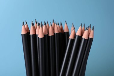 Açık mavi arkaplanda birçok keskin grafit kalem, yakın plan