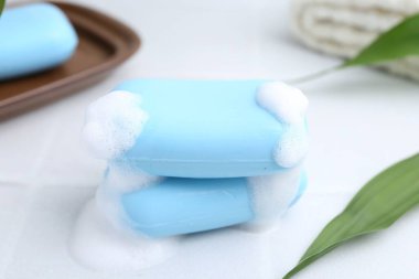 Beyaz masadaki köpüklü sabun çubukları, yakın plan.