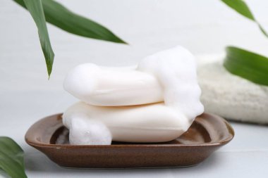 Beyaz masadaki köpüklü sabun çubukları, yakın plan.