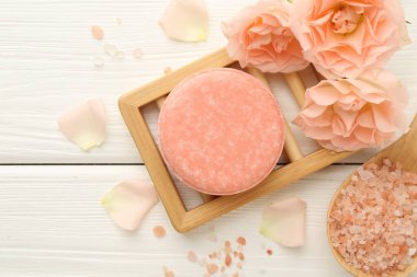 Sabun çubuğu, deniz tuzu ve beyaz ahşap masada güzel çiçekler, düz uzanmış.