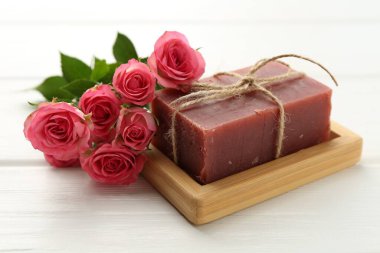 Sabun barı ve beyaz ahşap masada güzel güller, yakın plan.