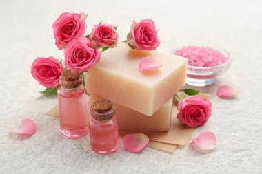 Sabun çubukları, deniz tuzu, temel yağlar ve bej masadaki güzel güller, yakın plan.