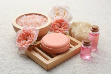 Sabun, deniz tuzu, temel yağlar ve bej masadaki güzel güller, yakın plan.