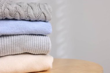 Yünlü süveter yığını ahşap masanın üzerinde, arka planda ışığa karşı, yakın plan. Metin için boşluk