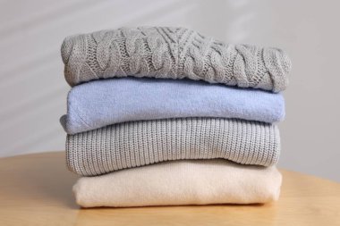 Yünlü süveter yığını ahşap masada, arka planda ışığa karşı, yakın plan