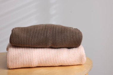 Yünlü süveter yığını ahşap masada, arka planda ışığa karşı, yakın plan