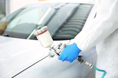 Kaportacıda çalışan bir işçi araba boyuyor, yakın plan.