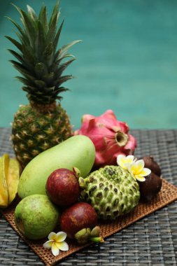 Yüzme havuzu yakınındaki hasır masada farklı bir tropik meyve.