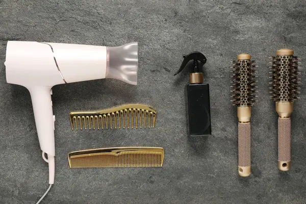 Gri dokulu arka planda farklı saç şekillendirme araçları, düz yatış