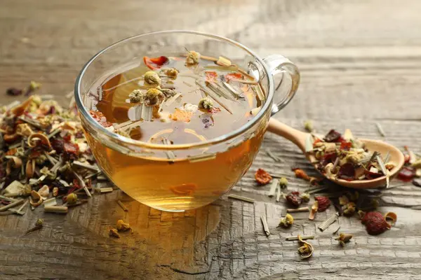 Lezzetli bitkisel çay ve kuru yapraklar ahşap masada, yakın plan.