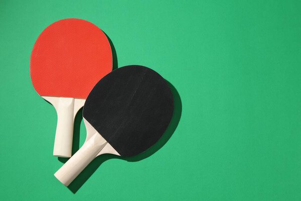 Ping pong rackets on green background, top view. Space for text