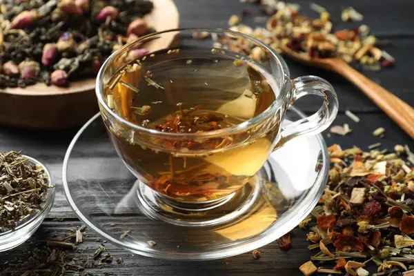 Bitki çayı ve kuru yaprakları siyah ahşap masada serinletiyor.