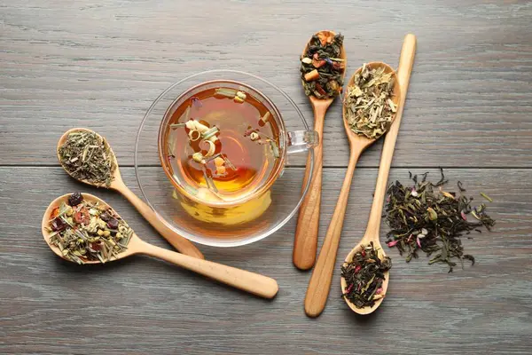 Cam bardakta Aromatik bitki çayı ve ahşap masada kuru yapraklar.