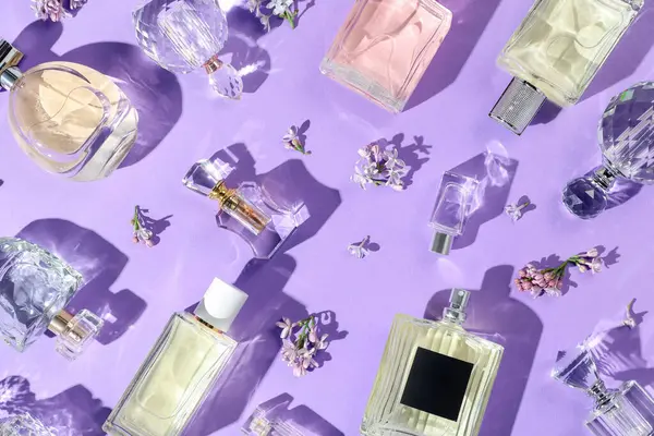 Düz kompozisyon, parfüm şişeleri ve mor arka planda leylak çiçekleri vardı.