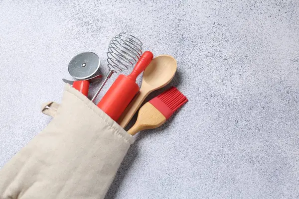 Farklı mutfak gereçleri fırın eldivenlerinde, ışık masasının üstünde, manzaranın üstünde. Metin için boşluk