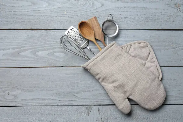 Fırın eldivenindeki farklı mutfak aletleri açık gri ahşap masa, üst manzara. Metin için boşluk
