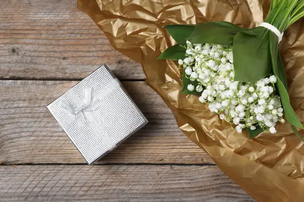 Bir buket güzel vadi zambağı ve ahşap arka planda bir hediye.
