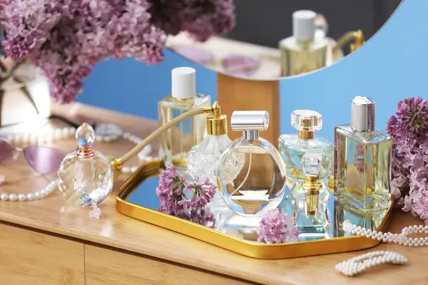 Parfümlü şişeler, eflatun çiçekleri ve tuvalet masasında aksesuarlar.
