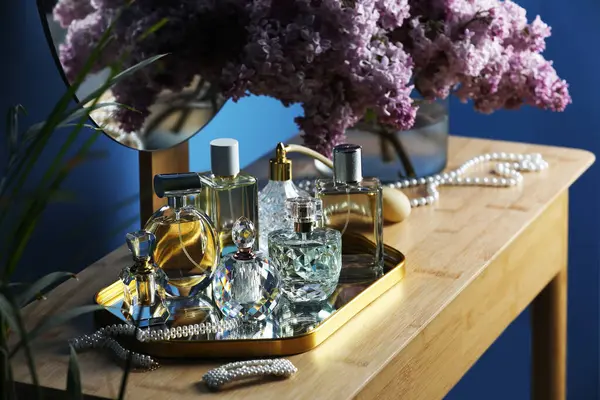 Parfümlü şişeler, eflatun çiçekleri ve tuvalet masasında aksesuarlar.
