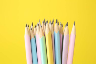 Sarı arkaplanda birçok grafit kalem, yakın plan