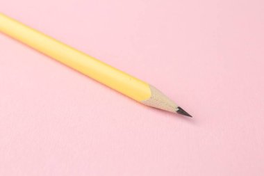 Pembe arka planda bir grafit kalem, yakın plan.