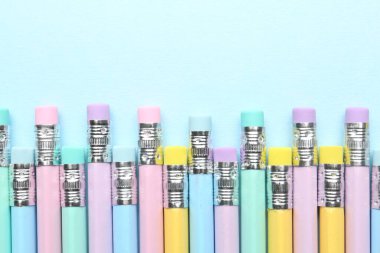 Açık mavi arkaplanda silgileri olan çizgili kalemler, düz. Metin için boşluk