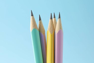 Many graphite pencils on light blue background, closeup