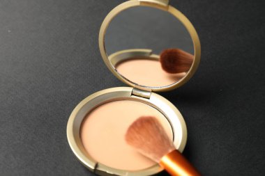 Aynalı yüz pudrasını aç ve siyah arkaplanda fırçala, kapat