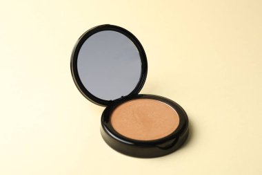 Bej arkaplanda aynalı açık yüz pudrası, yakın plan