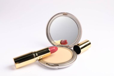 Aynalı yüz pudrası ve beyaz arka planda ruj.