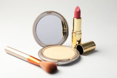 Açık gri arkaplanda ayna, fırça ve ruj ile yüz pudrası, yakın plan