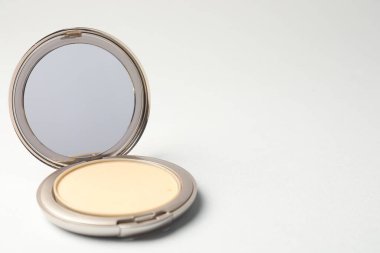 Açık yüz pudrası açık gri arka planda ayna, yakın plan. Metin için boşluk