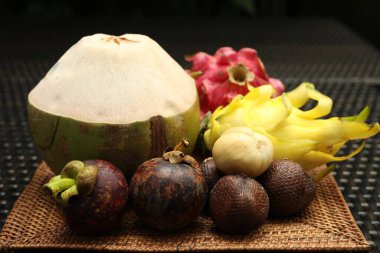 Hasır masada farklı tropik meyveler, yakın plan.