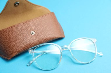 Açık mavi arka planda şık gözlüklü çanta, yakın plan