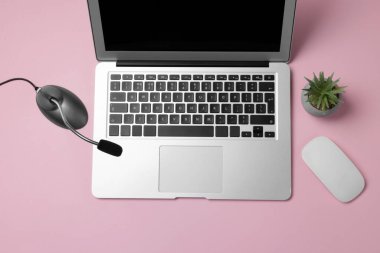 Profesyonel mikrofon, dizüstü bilgisayar, fare ve çiçek dekoru pembe arka planda, düz konum