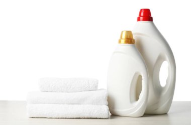 Beyaz arka plana karşı ahşap masa üzerinde yumuşatıcı ve havlu şişeleri