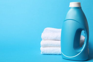 Açık mavi arkaplanda yumuşatıcı ve havlu şişesi, metin için boşluk