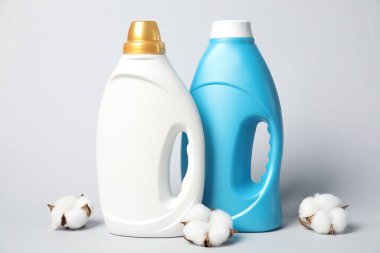 Kumaş yumuşatıcı şişeler ve açık gri arkaplanda pamuk çiçekleri