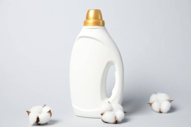 Bir şişe yumuşatıcı ve açık gri arkaplanda pamuk çiçekleri.