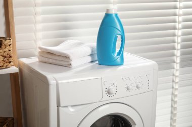 Bir şişe yumuşatıcı ve çamaşır makinesinin üzerindeki havlular.