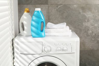 İçerideki çamaşır makinesinde yumuşatıcı ve havlu şişeleri.