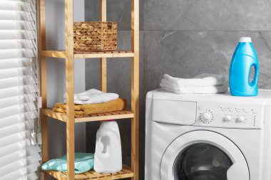 Bir şişe yumuşatıcı ve çamaşır makinesinin üzerindeki havlular.