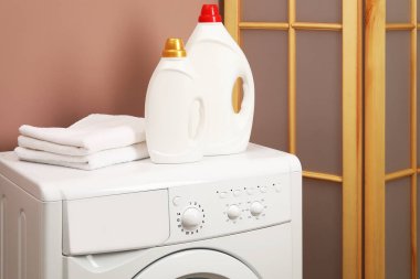 İçerideki çamaşır makinesinde yumuşatıcı ve havlu şişeleri.