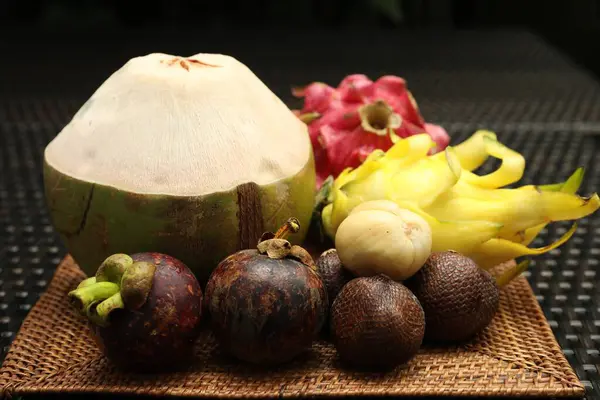 Hasır masada farklı tropik meyveler, yakın plan.