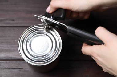 Kadın konserve açacağıyla konserve açıyor ahşap masada, üst manzara