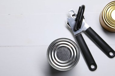 Konserve açacağı ve teneke kutular beyaz ahşap masada, düz yerde. Metin için boşluk