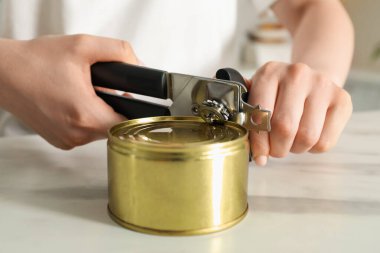 Beyaz masada konserve açacağıyla konserve açan kadın, yakın çekim