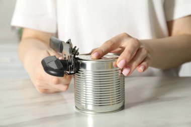 Beyaz masada konserve açacağıyla konserve açan kadın, yakın çekim