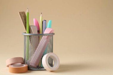 Bej arka planda kalem tutacağında farklı bir kırtasiye malzemesi. Metin için boşluk