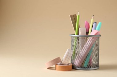 Bej arka planda kalem tutacağında farklı bir kırtasiye malzemesi. Metin için boşluk